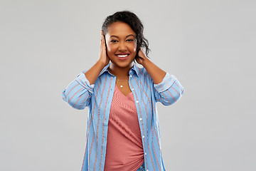 Image showing happy african american woman closing ears by hands