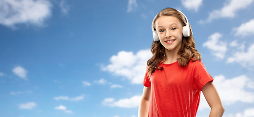 Image showing happy teenage girl in headphones over sky