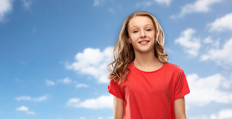 Image showing smiling teenage girl in red t-shirt over sky