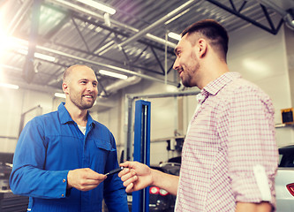 Image showing auto mechanic giving key to man at car shop