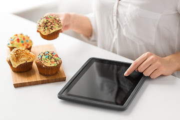 Image showing close up of woman with tablet pc and cupcake