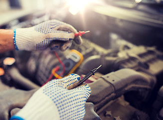 Image showing auto mechanic man with multimeter testing battery