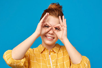 Image showing red haired teenage girl making finger glasses