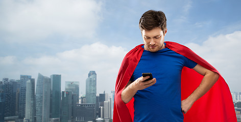 Image showing man in superhero cape using smartphone over city