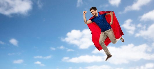 Image showing man in red superhero cape flying over sky