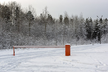 Image showing Barrier blocked the car passage on some terrain in winter snowy forest