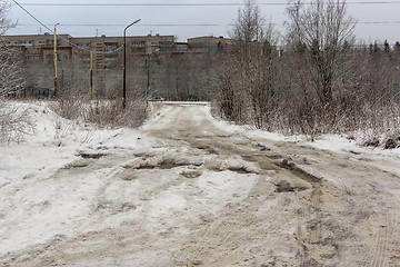 Image showing Bad road with deep holes, water, ice and snow in Russian city in winter