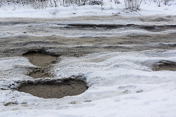 Image showing Road with deep holes, water, ice and snow in Russian city in winter