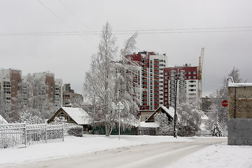 Image showing Old wooden houses on background of new tall city houses in winter