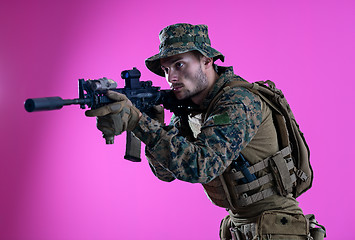 Image showing soldier in action aiming laseer sight optics pink background