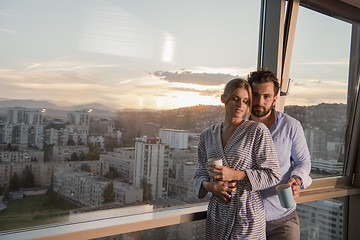 Image showing young couple enjoying evening coffee by the window