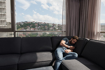 Image showing young casual man using a mobile phone at home