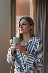 Image showing young woman enjoying evening coffee by the window