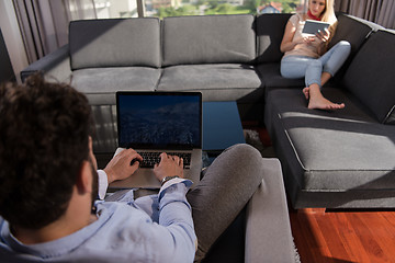 Image showing couple relaxing at  home using tablet and laptop computers