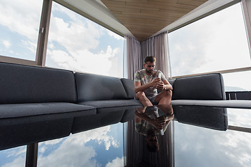 Image showing young casual man using a mobile phone at home