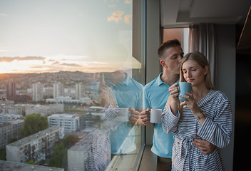 Image showing young couple enjoying evening coffee by the window