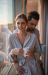 Image showing young couple enjoying evening coffee by the window