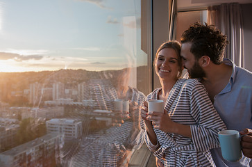 Image showing young couple enjoying evening coffee by the window