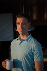 Image showing young man enjoying evening coffee by the window