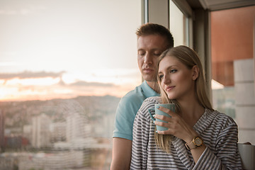 Image showing young couple enjoying evening coffee by the window