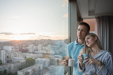 Image showing young couple enjoying evening coffee by the window