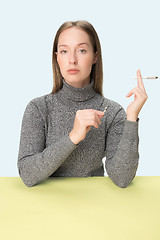 Image showing Handsome young women smoking while sitting at table at studio. Trendy colors