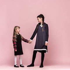 Image showing Cute stylish children on pink studio background. The beautiful teen girls standing together