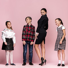 Image showing Cute stylish children on pink studio background. The beautiful teen girls and boy standing together