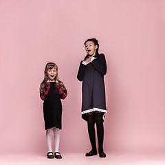 Image showing Cute stylish children on pink studio background. The beautiful teen girls standing together