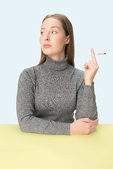 Image showing Handsome young women smoking while sitting at table at studio. Trendy colors