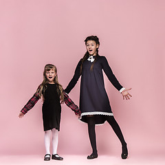 Image showing Cute stylish children on pink studio background. The beautiful teen girls standing together