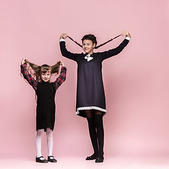 Image showing Cute stylish children on pink studio background. The beautiful teen girls standing together