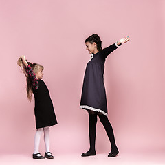 Image showing Cute stylish children on pink studio background. The beautiful teen girls standing together