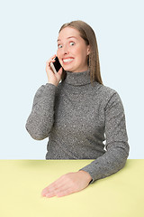 Image showing The happy business woman sitting with mobile phone against pink background.
