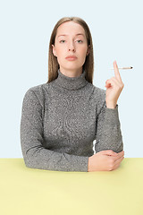 Image showing Handsome young women smoking while sitting at table at studio. Trendy colors
