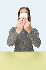 Image showing The happy business woman sitting with mobile phone against pink background.