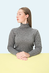 Image showing Serious business woman sitting at a table on a pink background