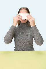 Image showing The happy business woman sitting with mobile phone against pink background.