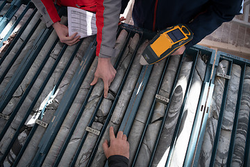 Image showing team of mining  workers measuring drilled rock core