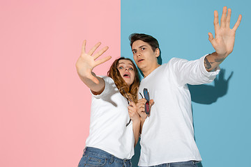 Image showing Young emotional man and woman on pink and blue background