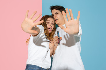 Image showing Young emotional man and woman on pink and blue background