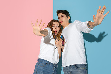 Image showing Young emotional man and woman on pink and blue background