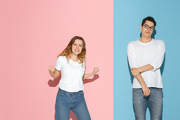 Image showing Young emotional man and woman on pink and blue background