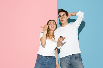 Image showing Young emotional man and woman on pink and blue background