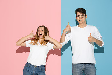 Image showing Young emotional man and woman on pink and blue background