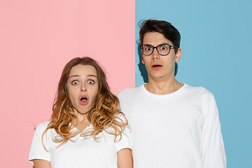 Image showing Young emotional man and woman on pink and blue background