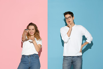 Image showing Young emotional man and woman on pink and blue background