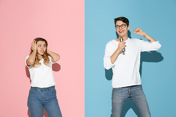 Image showing Young emotional man and woman on pink and blue background