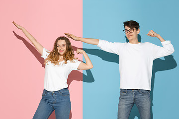 Image showing Young emotional man and woman on pink and blue background