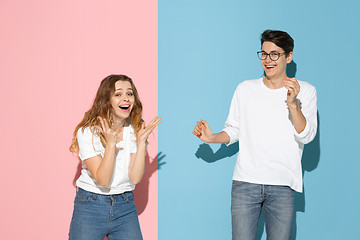 Image showing Young emotional man and woman on pink and blue background